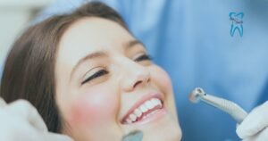 A dentist holding a dental drill near a patient's mouth. The image is partially blurred, focusing on the dental tool, with the 'tru Smile' logo visible in the background.